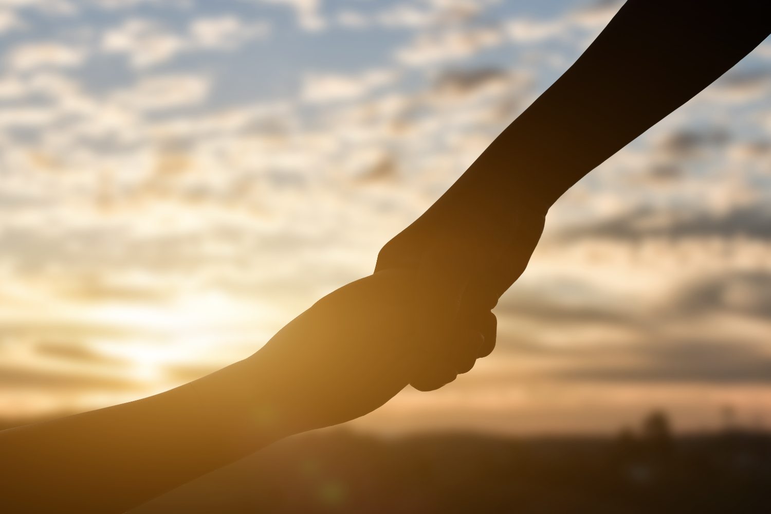 silhouette-of-giving-a-help-hand-hope-and-support-2025-01-09-09-49-15-utc (1) Käsi kädessä, auringonpaiste taustalla.
